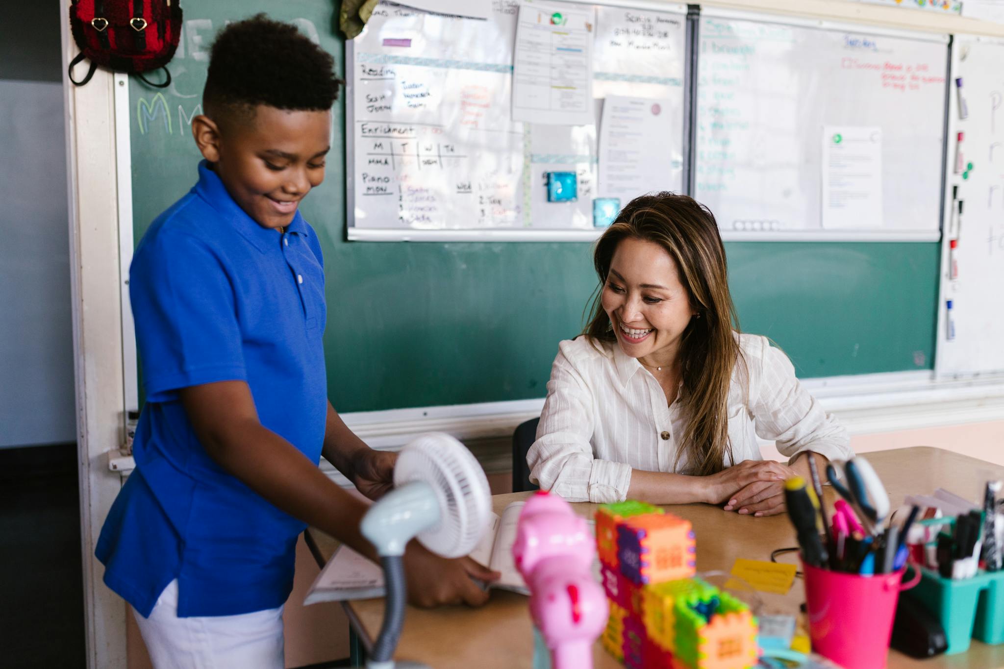 A smiling teacher assisting a student in an inspiring classroom setting.