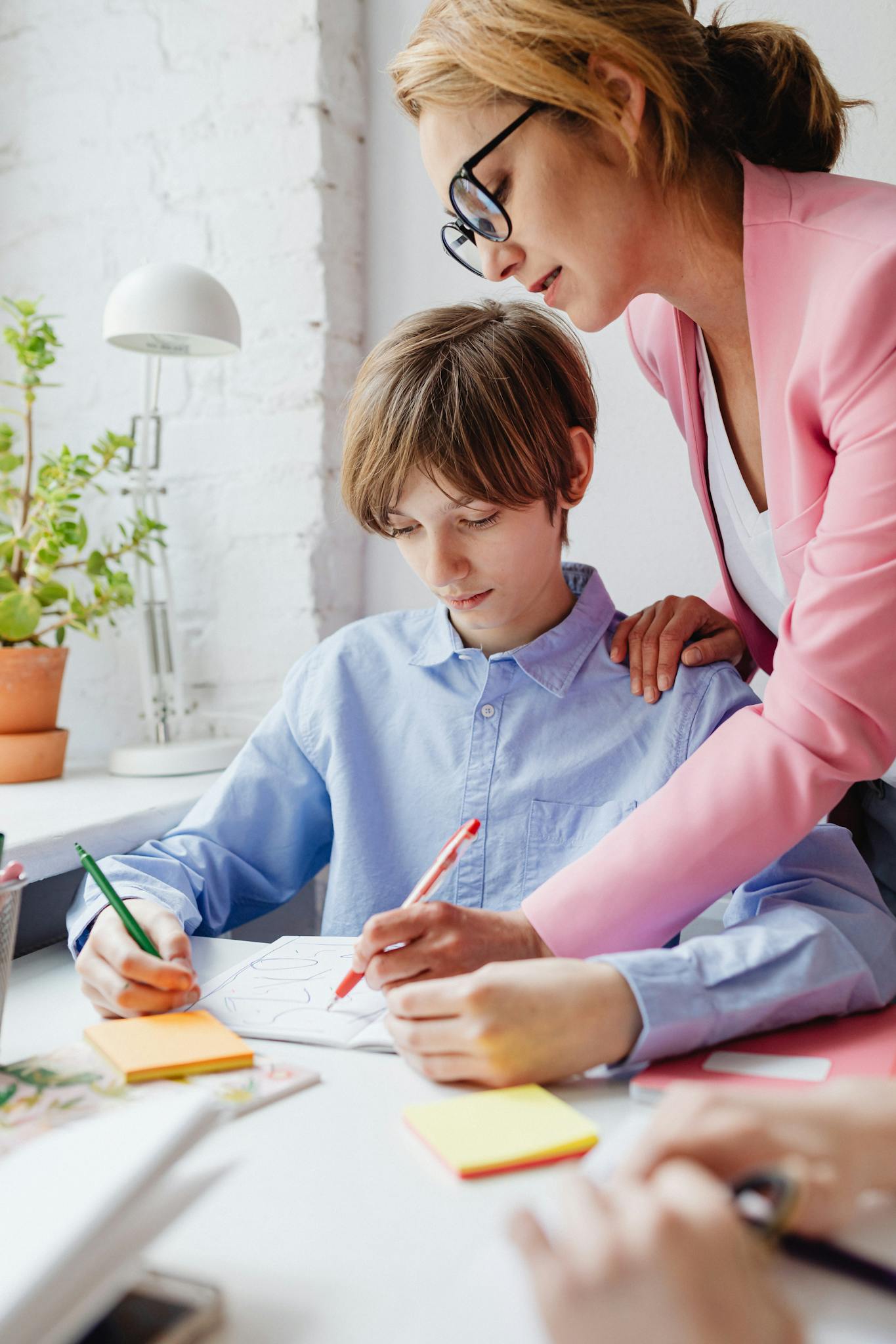 Teacher helping a student with homework at a desk indoors.